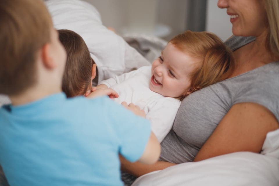 A family laughing together in bed